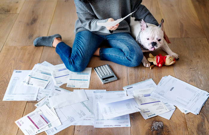 recent college graduate surrounded by bills on floor with a dog
