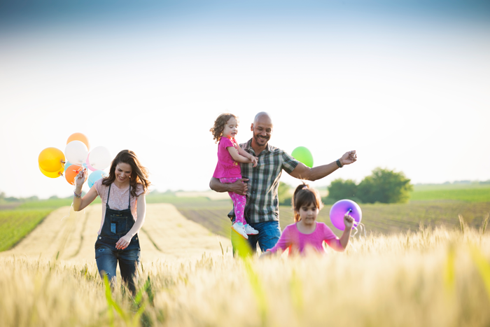 happy family walking through field with balloons